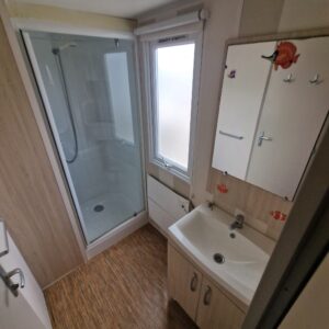 Baño con cabina de ducha con mampara y lavabo